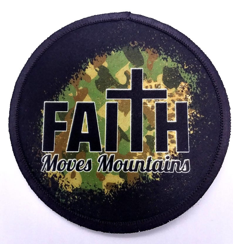 Round iron-on patch with the text "Faith Moves Mountains" printed in black on top of a camouflage background.