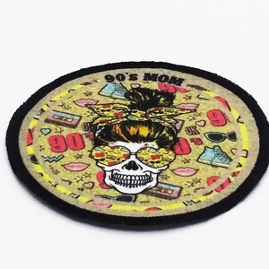 Round iron-on patch with retro 90s mom illustration, skull graphic, and colorful full-print design finished with a black merrowed edge.
