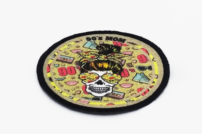 Round iron-on patch with retro 90s mom illustration, skull graphic, and colorful full-print design finished with a black merrowed edge.