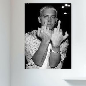 May include: Black and white photo of a man with short hair wearing a patterned shirt. He is making a rude gesture with both hands.