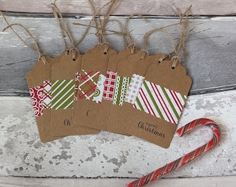 May include: A collection of brown paper gift tags with decorative patterned paper accents in red and green. Each tag has a jute string and the words "Happy Christmas" printed on it. A candy cane rests on the surface.