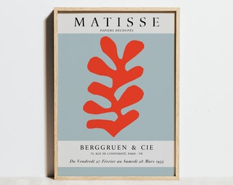 May include: A vintage poster for an art exhibition featuring a red cutout of a stylized leaf on a light blue background. The poster is titled "MATISSE PAPIERS DÉCOUPÉS" and includes the text "BERGGRUEN & CIE 70, RUE DE L'UNIVERSITÉ, PARIS - VII Du Vendredi 27 Février au Samedi 28 Mars 1953."