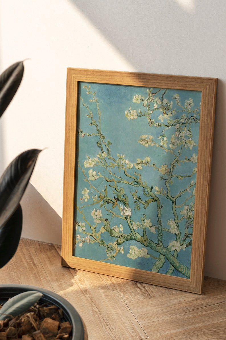 May include: A framed painting of a blooming almond tree with white flowers against a blue sky. The painting is in a light wood frame.