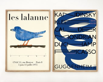 May include: Two framed posters with a white background. The left poster features a blue bird with an orange beak and legs. The right poster features a blue abstract shape with the text "Kandinsky, Klee, Calder, Mondrian, Duchamp, Picasso, Guggenheim" in black.