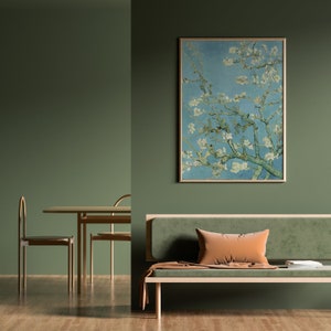 May include: A green living room with a light green sofa, a wooden coffee table, and two chairs. A framed painting of a blooming tree branch hangs on the wall.