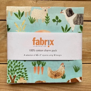 May include: A bundle of fabric squares featuring a farm animal design with sheep, a dog, a chicken, and carrots on a light blue backdrop. The fabric is wrapped with a white band that reads "fabrix" and "100% cotton charm pack". Each square is 12.7 cm.