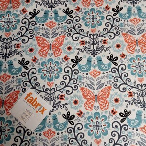 May include: A white fabric with a repeating pattern of teal blue birds, orange butterflies, and black floral designs. The fabric has a vintage feel and is perfect for crafting projects.