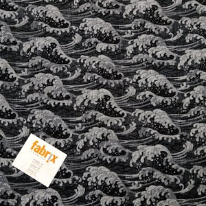 May include: Black fabric with a white wave pattern. The fabric has a textured surface and a subtle sheen. The fabric is perfect for creating unique and stylish projects.