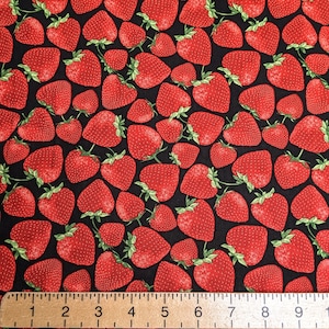 May include: A black fabric with a repeating pattern of red strawberries. A ruler is placed at the bottom of the image with numbers 1 through 10.