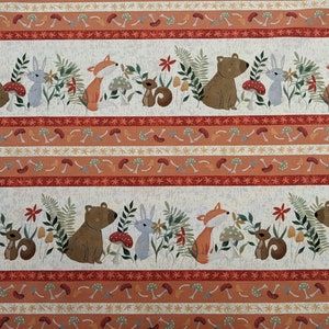 May include: A white fabric with a repeating pattern of brown bears, foxes, rabbits, and squirrels in a woodland setting. The pattern includes red, orange, and yellow mushrooms, green leaves, and brown branches. The fabric has a white background with orange, red, and yellow stripes.