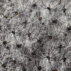 May include: A black and white fabric with a spiderweb pattern and black spiders with orange markings.