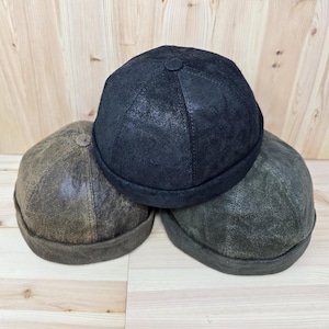 May include: Three leather hats in different shades of brown and black. The hats are stacked on top of each other. The hats are made of a soft, supple leather.