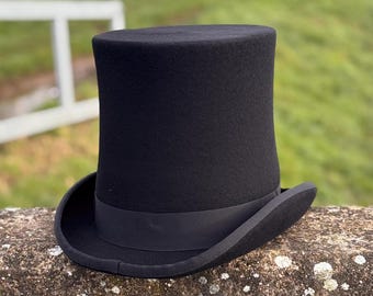 May include: A black top hat with a black band around the base. The hat is made of felt and has a tall, cylindrical crown.