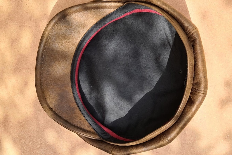 May include: A brown leather cap with a black lining and a red trim around the inside.
