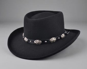 May include: A black felt hat with a flat crown and a curved brim. A black leather band encircles the base of the crown, featuring evenly spaced silver-toned oval metal conchos with embossed sunburst patterns and small silver studs between them.