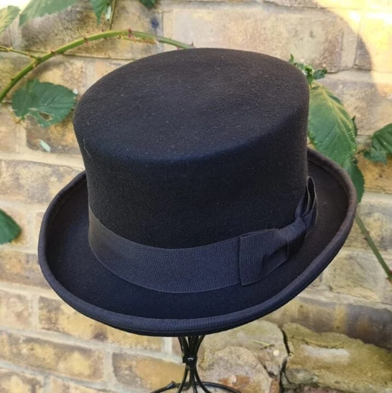 May include: A black top hat with a black ribbon band. The hat is made of felt and has a tall, cylindrical crown.