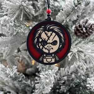 May include: A round wooden Christmas ornament featuring a black and white illustration of a character with a red background. The character has a stitched face and is wearing overalls.