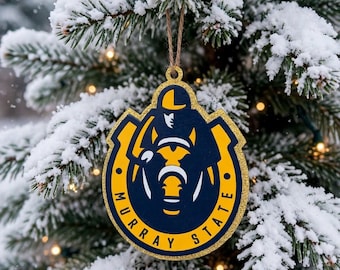 May include: A Murray State University ornament featuring a navy blue and gold horse mascot logo with the text Murray State printed in gold. The ornament has a gold glitter border and is suspended by a thin brown twine string.