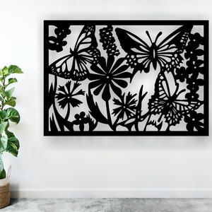 May include: Black metal wall art featuring a silhouette of butterflies and flowers. The design is intricate and detailed, with delicate lines and curves.