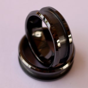 May include: Two black tungsten carbide rings with beveled edges. The rings are stacked on top of each other.