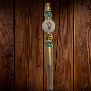May include: Gold pen with a white and green iced coffee cup design. The pen is decorated with rhinestones.
