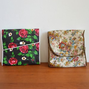 Könnte beinhalten: Zwei Stoffbeutel mit Blumenmuster. Der Beutel links hat einen schwarzen Hintergrund mit roten Rosen und grünen Blättern. Der Beutel rechts hat einen cremefarbenen Hintergrund mit einem Blumenmuster. Beide haben einen Knopfverschluss.