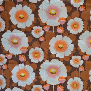 Könnte beinhalten: Ein brauner Stoff mit einem weißen Blumenmuster. Die Blumen haben rosa Zentren und orangefarbene Akzente.