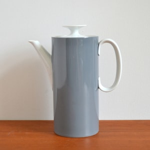 Könnte beinhalten: Eine graue Kaffeekanne aus Keramik mit einem weißen Deckel und Griff. Die Kanne hat ein schlankes, modernes Design.