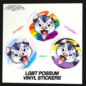 May include: Set of four round vinyl stickers featuring a cartoon possum with different expressions and backgrounds. The backgrounds include a rainbow, a transgender pride flag, a genderqueer pride flag, and a purple, yellow, and black flag. The text "SO ANGY!!!", "GRRR!!!", "SO QUEER!!!", and "LGBT POSSUM VINYL STICKERS" is included on the stickers.
