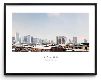 May include: A panoramic view of Lagos, Nigeria, with a skyline of modern skyscrapers and a foreground of densely packed residential buildings. The sky is a light blue with some clouds.