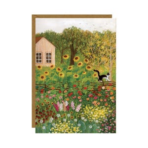 Könnte beinhalten: Grußkarte mit einer farbenfrohen Gartenszene. Eine schwarz-weiße Katze geht an einem Holzzaun entlang. Sonnenblumen und verschiedene Blumen blühen im Garten, mit einem kleinen Haus im Hintergrund. Die Karte hat einen braunen Rand.