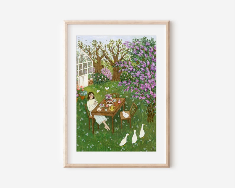 May include: A framed art print depicts a serene outdoor scene. A person sits at a table set for tea in a lush green garden, surrounded by flowering trees and white ducks. The artwork is in a light, airy style, with soft colors.