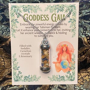 May include: A silver-toned pendant necklace featuring a clear cylindrical vial filled with small blue sodalite and orange carnelian crystals, attached to a display card with the text Goddess Gaia and a graphic illustration of a seated figure.