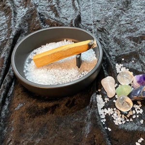 Könnte beinhalten: Ein Set aus drei Keramikbechern mit gesprenkelter, matter Oberfläche. Die Becher sind in Creme-, Hellgrau- und Dunkelgrautönen gehalten. Jeder Becher hat ein schlichtes, modernes Design und einen abgerundeten Henkel.