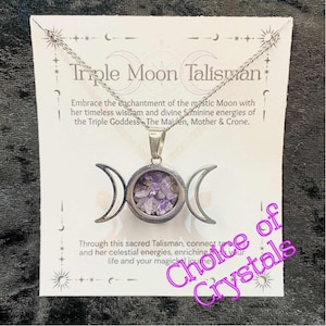 May include: A silver necklace with a Triple Moon Talisman pendant. The pendant has a circular centre filled with purple crystals, with crescent moons on either side. The card behind the necklace reads "Triple Moon Talisman".
