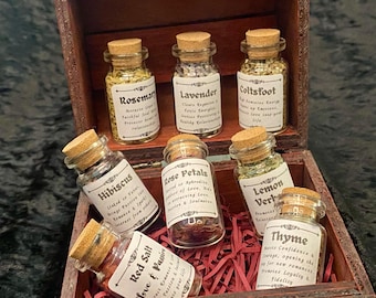 May include: A wooden box filled with small glass bottles containing dried herbs and flowers. Each bottle has a label with the name of the herb or flower and a description of its properties. The herbs and flowers include rosemary, lavender, coltsfoot, hibiscus, rose petals, lemon verbena, and thyme.