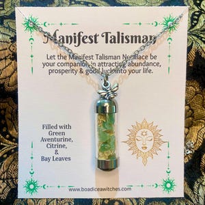 May include: A silver necklace featuring a glass vial pendant filled with green aventurine, citrine, and bay leaves. The vial is topped with a silver bee charm. The card reads "Manifest Talisman".