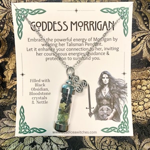 May include: A silver necklace with a pendant containing black obsidian, bloodstone crystals, and nettle. The pendant is a small glass vial with silver metal caps. The card behind the necklace reads "GODDESS MORRIGAN" and includes text about the pendant's purpose.