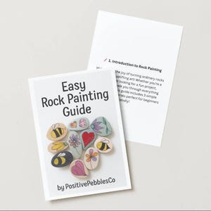 May include: A white booklet titled "Easy Rock Painting Guide" with illustrations of painted rocks, including bees and flowers. The guide is by PositivePebblesCo. An additional page provides an introduction to rock painting.
