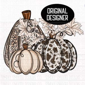 May include: Three pumpkins with a brown and white leopard print, a brown and white cow print, and a beige color. The pumpkins are arranged in a row with the leopard print pumpkin in the back and the cow print pumpkin in the front. The pumpkins are surrounded by brown leaves.