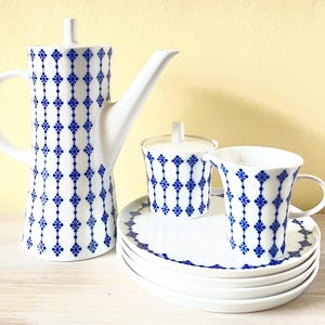 Könnte beinhalten: Eine weiße Porzellan-Kaffeekanne, eine Milchkännchen und eine Tasse mit einem blauen und weißen Blumenmuster. Das Set enthält einen Unterteller und vier zusätzliche Unterteller.