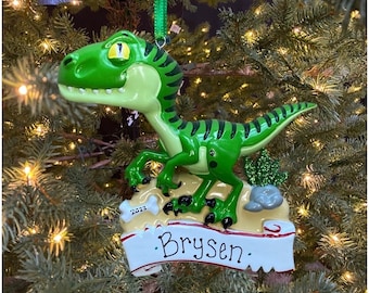 May include: Green dinosaur Christmas ornament with a banner that says "Brysen" and the year "2023".