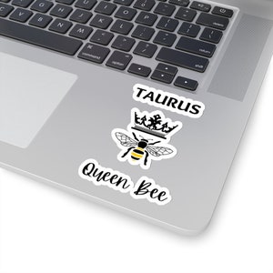 Könnte beinhalten: Ein schwarz-weißer Aufkleber mit dem Text "Taurus" und "Queen Bee" mit einer schwarz-gelben Biene, die eine Krone trägt.