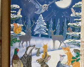 Può includere: Un biglietto di auguri con una scena di foresta invernale con animali. Un gufo vola di fronte a una luna piena, con cervi, volpi e altri animali in un paesaggio innevato. Il biglietto ha un bordo marrone.