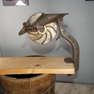 May include: Antique cast iron cherry pitter with a wooden base. The pitter has a handle with the text "NEW STANDARD CHERRY STONER" and a round blade with the number "No. 16".