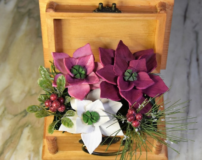 Small wood, suitcase, trunk, treasure chest, filled with pretty Sola wood poinsettias in shades of burgundy and pink with festive fillers