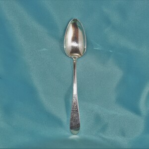 May include: A silver teaspoon with a rounded bowl and a long, slender handle.