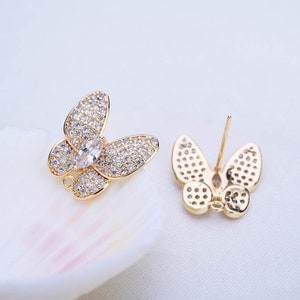May include: A pair of gold butterfly earrings with clear crystal accents. The earrings have a post back closure.