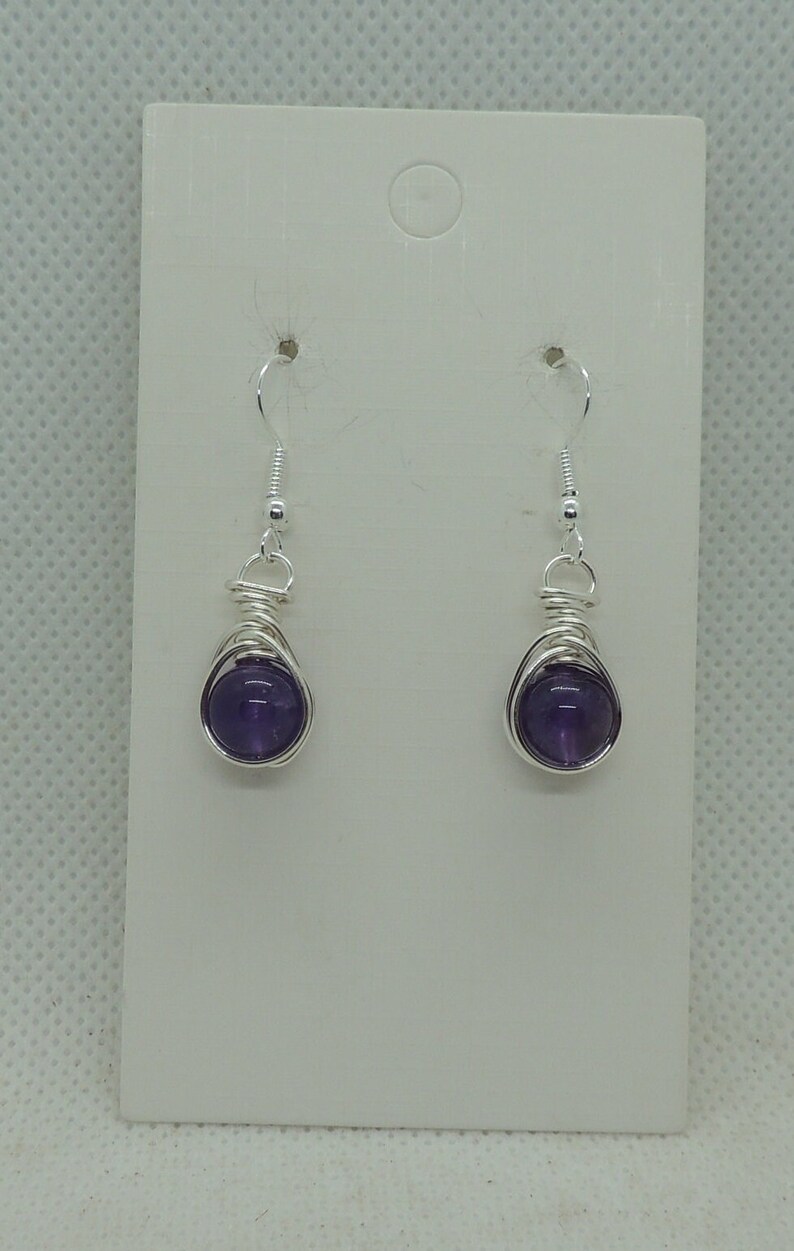 May include: A pair of silver wire wrapped earrings with amethyst stones.