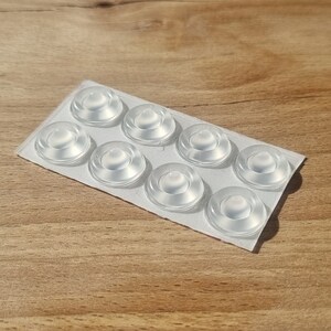 May include: A sheet of clear, round, adhesive pads for furniture.